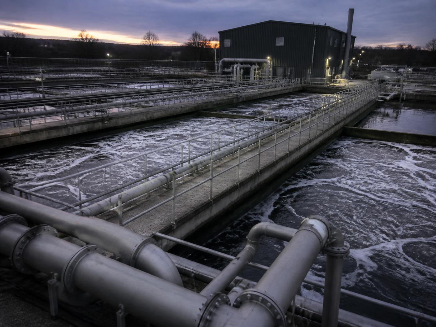 Aeration lanes and process pipework at a wastewater treatment works at dusk